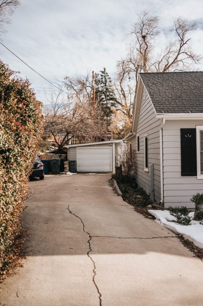 Suburban driveway with cracked, uneven pavement showing early signs of rut damage