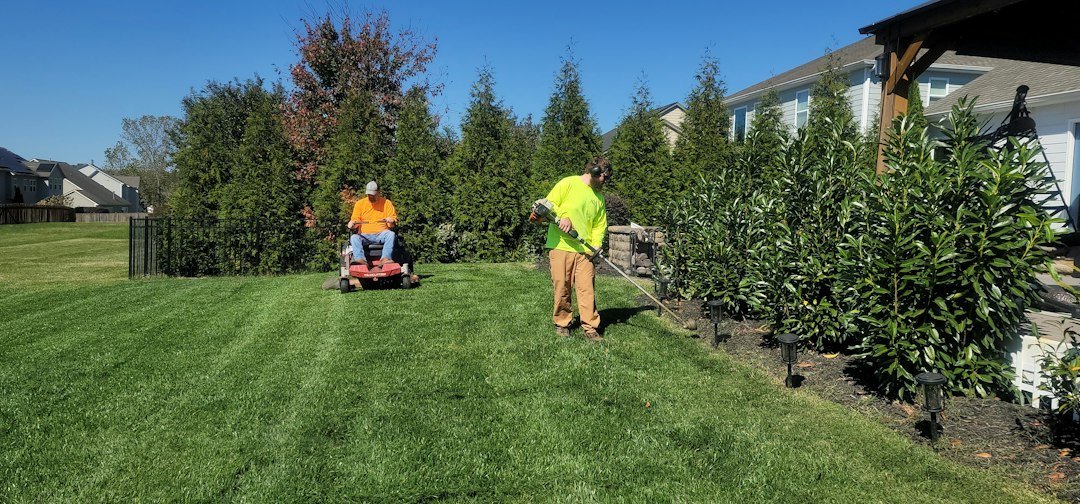 Landscaper mowing a lawn, a typical recurring route job managed with lawn care scheduling software