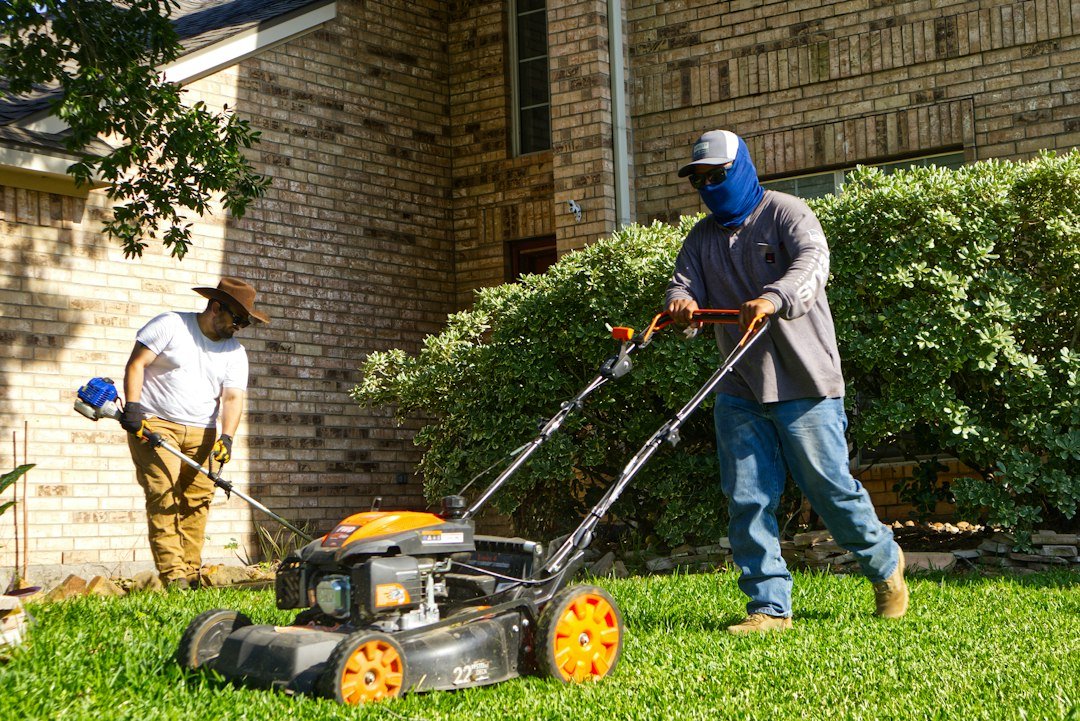 Lawn care crew mowing a residential lawn, illustrating field service management software for lawn care businesses
