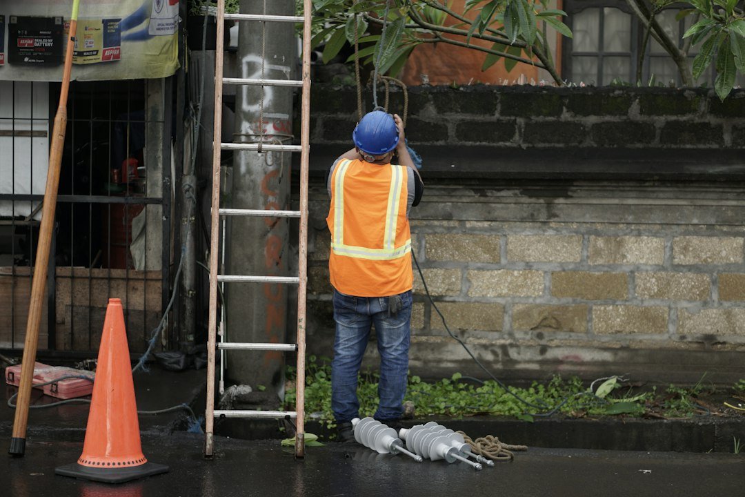 Maintenance worker wearing a hi-vis safety vest standing beside a ladder before starting work