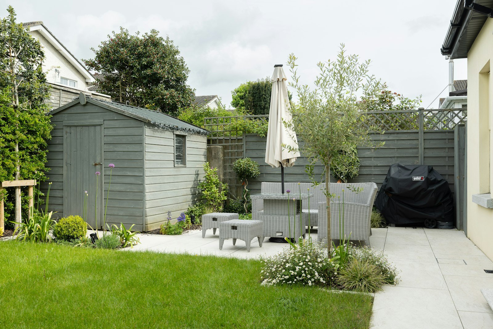Simple backyard patio with table, chairs, and umbrella, an example of an affordable landscape design